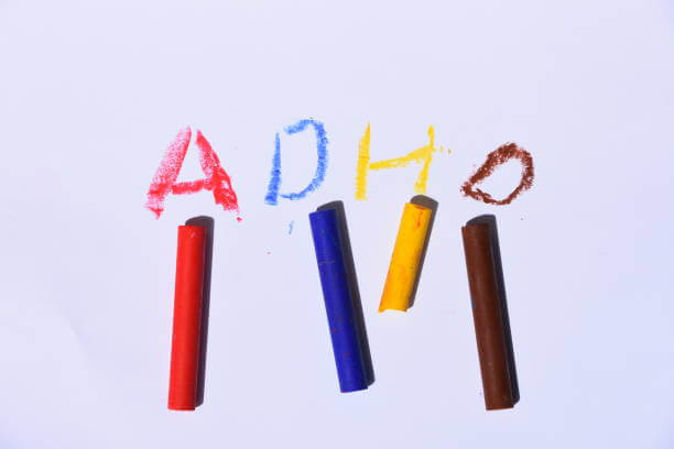 ADHD written on sheet of paper in different colored crayons