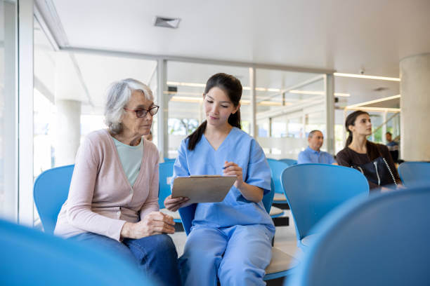 Nurse helping a senior woman fill her registration form at the hospital - medical insurance concepts