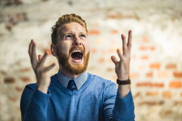 Frustrated businessman screaming of disappointment and looking up.